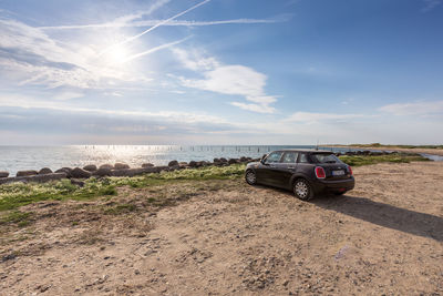 Car on sea shore against sky