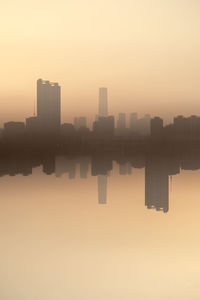 Reflection of cityscape against sky during sunset