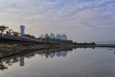 Reflection of buildings in lake against sky in city