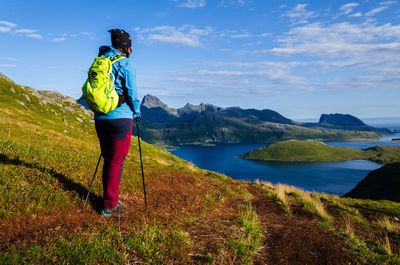 Rear view of man standing on mountain against sky
