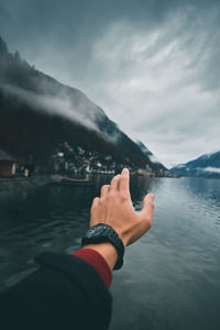 Midsection of person on lake against mountain range