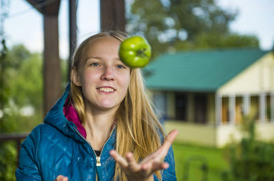 Young woman playing with green tomato