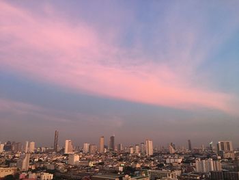 Modern buildings in city against sky during sunset