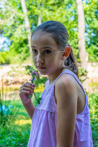 Cute girl holding plant standing outdoors