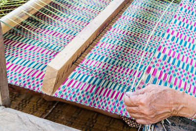 Cropped hand of person weaving thread in factory