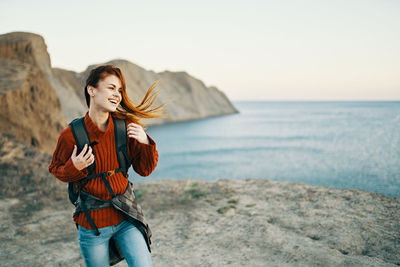Young woman standing in sea against sky