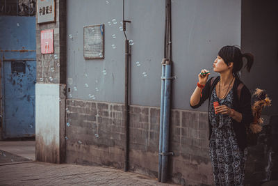 Side view of woman standing against wall