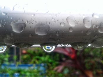 Close-up of water drops on glass against sky during rainy season