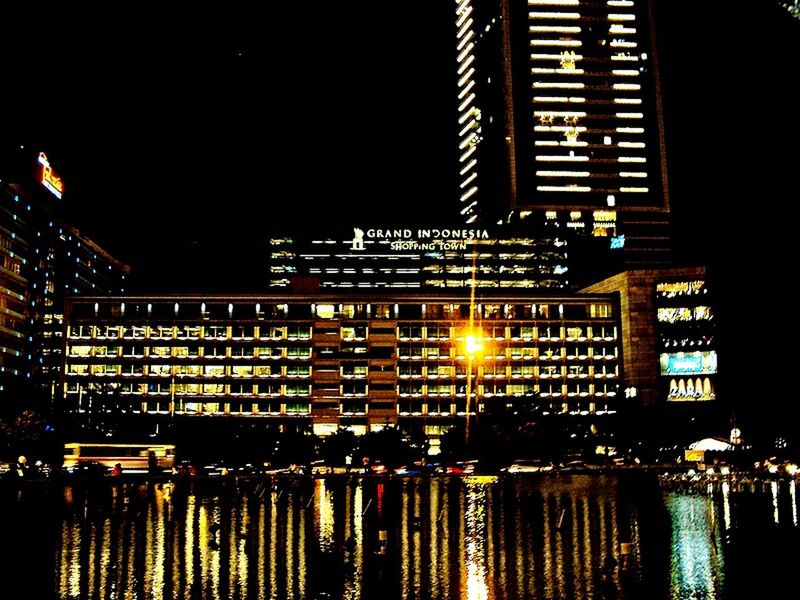 illuminated, night, architecture, building exterior, built structure, reflection, water, waterfront, city, building, river, clear sky, sky, residential building, no people, outdoors, dark, residential structure, lighting equipment, light - natural phenomenon