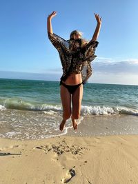 Full length of woman jumping at beach