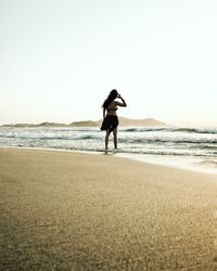Woman walking on beach against clear sky