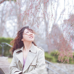 Young woman standing against trees