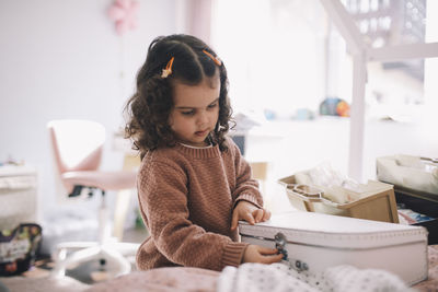 Girl closing box on bed at home