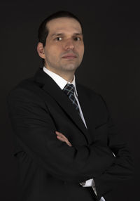 Portrait of young man standing against black background