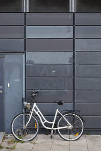 Bicycle parked on footpath against wall