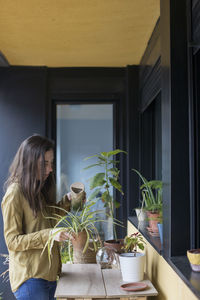 Woman standing by potted plants at home