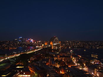 Illuminated cityscape against clear sky at night