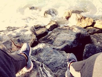 Low section of man standing on rock at beach