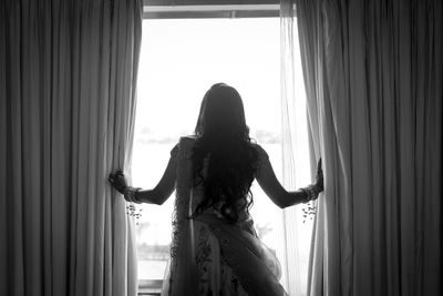 Rear view of woman standing by window