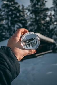 Close-up of person hand holding crystal ball on snow covered field during winter