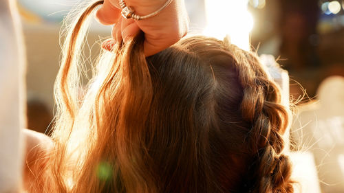 Cropped hands of female hairstylist styling girl hair