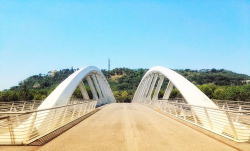 Footbridge over swimming pool against clear blue sky