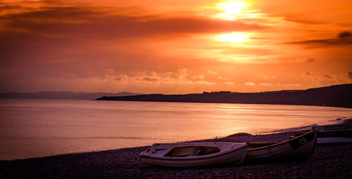 Boat moored on lake against sky during sunset