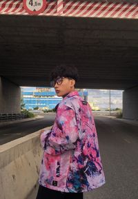 Boy looking down while standing against wall