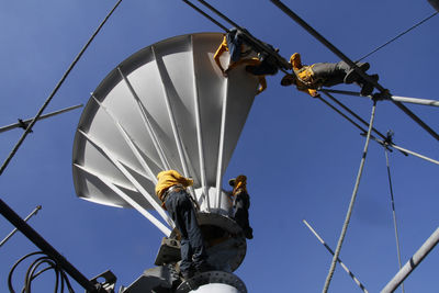 Low angle view of people against blue sky