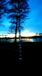 Silhouette trees by lake against sky at sunset