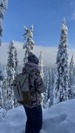 Rear view of man skiing on snow covered field