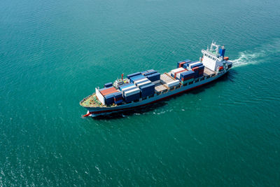 Aerial view in front container ship full speed in green sea, business and industry transportation 