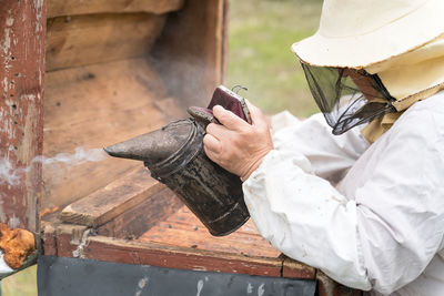 Beekeeper working with smoker outdoors