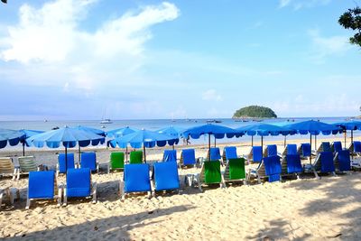 Deck chairs on beach against blue sky