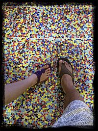 Low section of woman standing by multi colored shoes