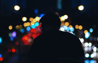 Rear view of silhouette man against illuminated lights