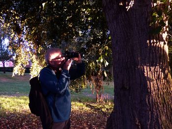 Mature man photographing tree