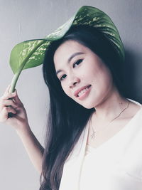 Close-up portrait of smiling woman holding leaf on hair