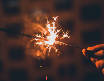 Close-up of hand holding illuminated sparkler at night