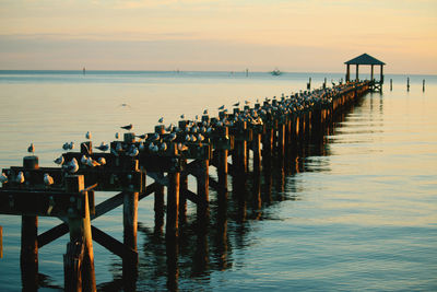 Pier over sea against sky during sunset