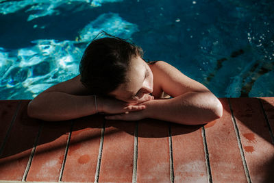 Tween girl resting head on the side of a swimming pool