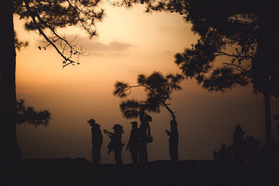 Silhouette people by tree against sky during sunset