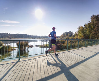 Rear view of man on footpath by lake against sky