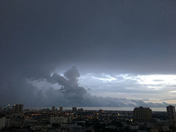 Buildings in city against storm clouds