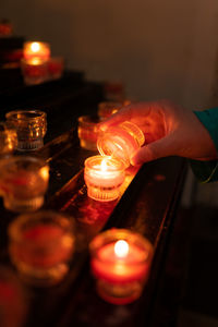 Cropped hand holding illuminated light candles