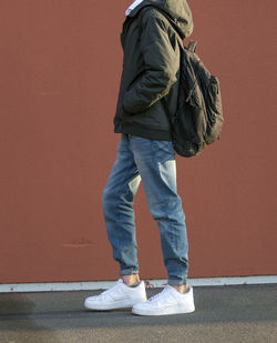 Low section of man standing against orange wall