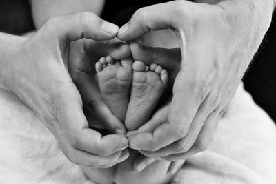 Cropped image of parents making heart shape with baby feet