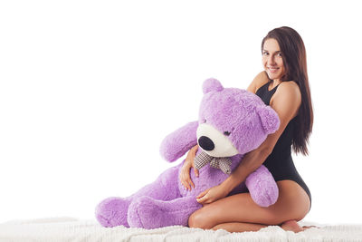 Portrait of smiling young woman sitting on bed against white background