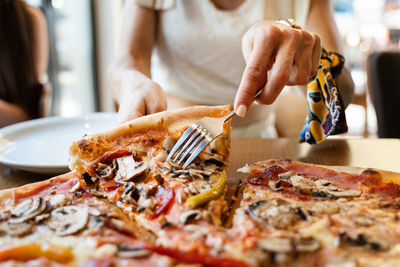 Midsection of person eating ice cream in restaurant