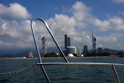 View of buildings by river against cloudy sky